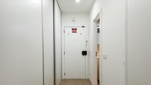 Un pasillo con una puerta blanca, un detector de incendios y un interruptor de luz.