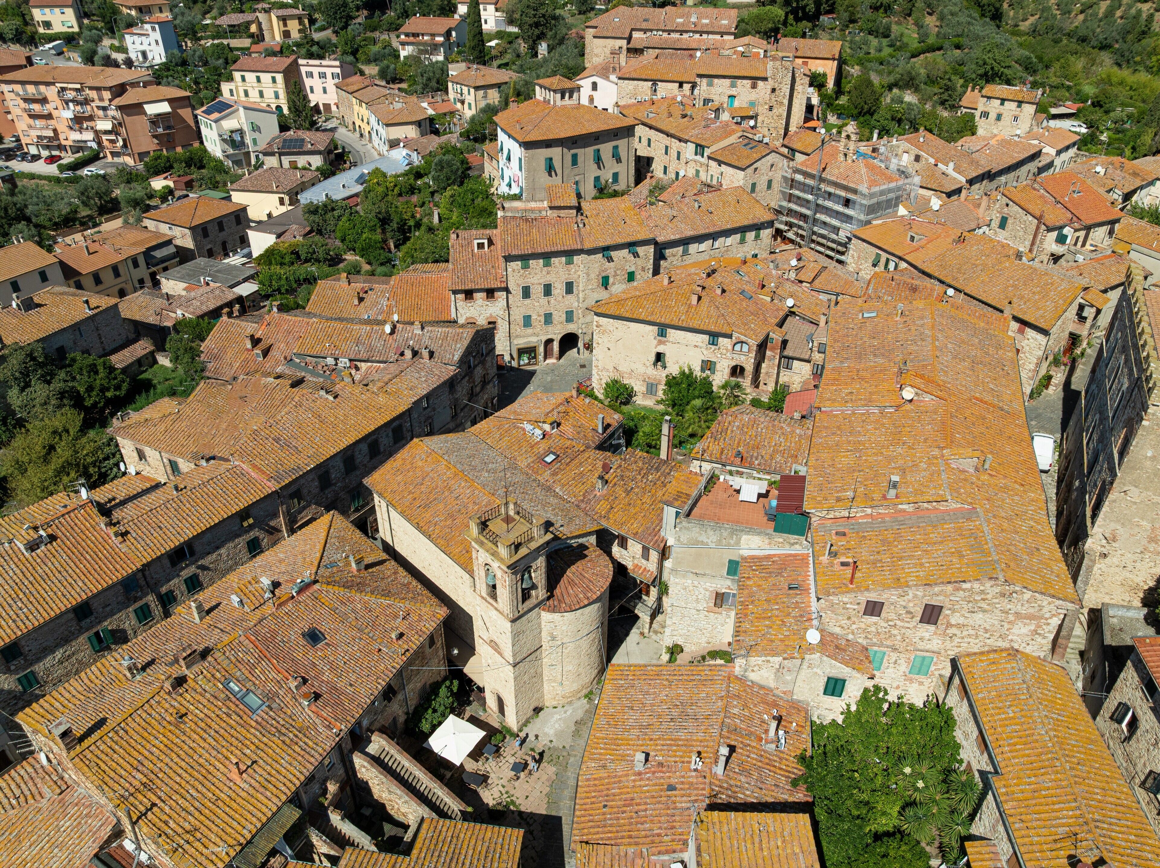 An aerial view of a historic town with closely packed buildings, cobblestone streets, and a prominent tower.