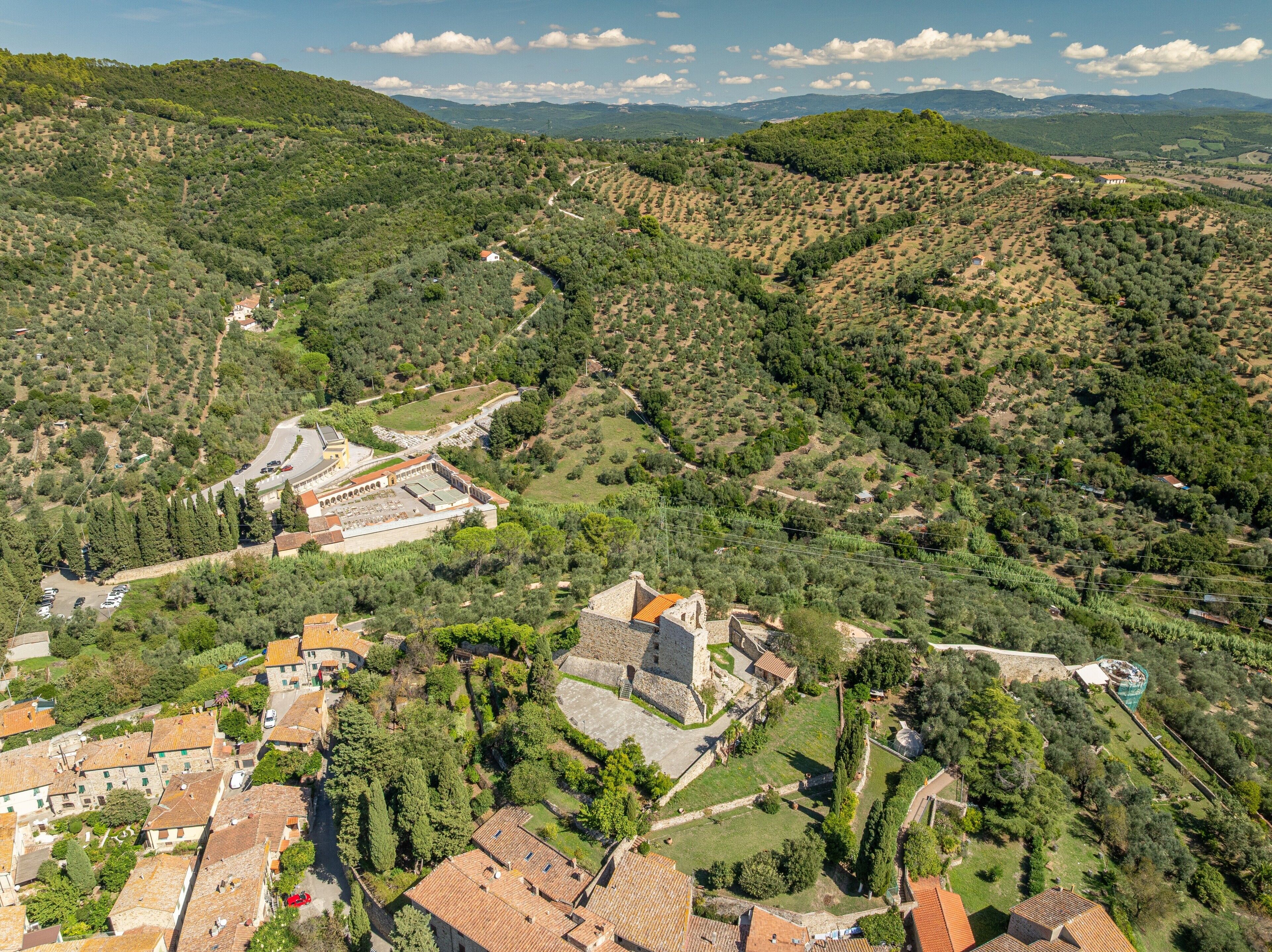 A historic town with terraced vineyards, a central square, and traditional stone buildings.