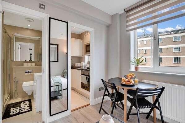 A modern apartment with a dining area, kitchen, and bathroom. - Prime Chelsea Studio – 5 Min to Tube -Quiet & Safe (London)