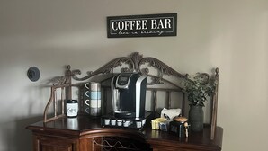 Ein Café-Arrangement mit Kaffeemaschine, Tasse und Zuckerbehälter auf einem Holzschrank.