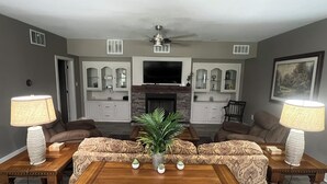 Ein Wohnzimmer mit Kamin, zwei Sofas, einem Couchtisch und einem Fernseher.