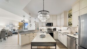 A modern kitchen with white cabinetry, stainless steel appliances, and a central island.