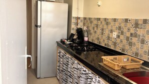 A compact kitchen with a refrigerator, a stove, and a sink. - Apartment with sea view and Santa Cruz (Oran)