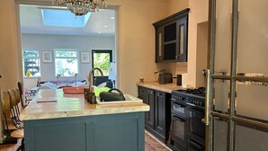 A modern kitchen with a central island, dark cabinetry, and a chandelier.