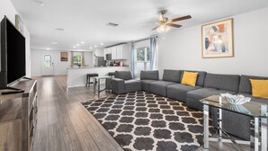 A modern living room with a sectional sofa, a glass coffee table, and a patterned rug.