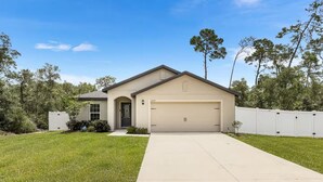 A single-story house with a garage, a front door, and a small front yard.