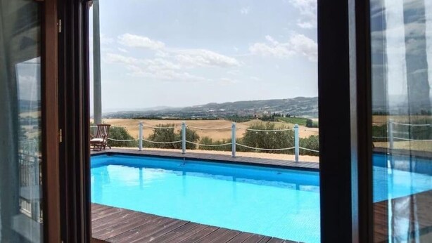 Blick vom Zimmerfenster auf einen Pool und eine reizvolle Landschaft.