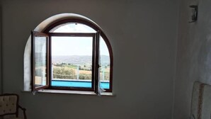 Ein Zimmer mit einem Bett, einem Sessel und einem Fenster mit Blick auf eine Landschaft.