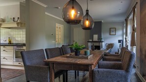 Ein Essbereich mit einem Holztisch, sechs Stühlen, einer Hängelampe und einer Küche im Hintergrund.
