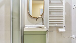 A modern bathroom with a glass shower enclosure, a white sink with a towel, a mirror, and a white toilet. - Superb Apartment Center of Paris (Paris)