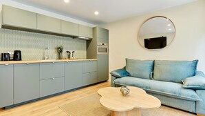 A modern kitchen with grey cabinets, a wooden countertop, and a round mirror on the wall. - Superb Apartment Center of Paris (Paris)
