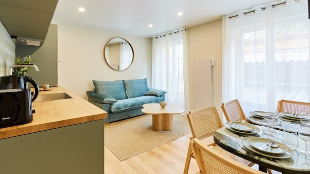 A modern living room with a sofa, a coffee table, and a dining area with chairs and a table set for two. - Superb Apartment Center of Paris (Paris)