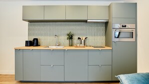 A compact kitchen with grey cabinets, a wooden countertop, a built-in oven, and a small sink. - Superb Apartment Center of Paris (Paris)