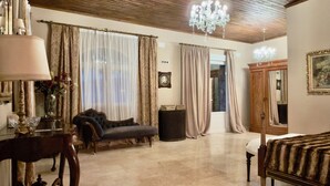 A room with a chandelier, curtains, a sofa, a table with a lamp, and a mirror. - PALACIO ARUDECAS (Cañada de Calatrava)