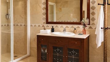 Un baño con cabina de ducha de vidrio, tocador de madera con lavamanos y un espejo grande sobre el tocador.