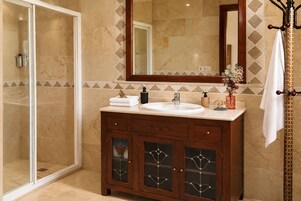 A bathroom with a glass shower enclosure, a wooden vanity with a sink, and a large mirror above the vanity.