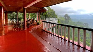 A covered outdoor area with wooden flooring and a curved railing overlooking a lush, mountainous landscape. - The - Hideaway Ella (Ella)