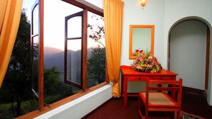 A room with a large window, a wooden table with a vase of flowers, and a mirror on the wall. - The - Hideaway Ella (Ella)