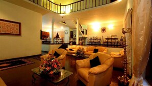 A spacious living area with leather sofas, a coffee table with flowers, and a staircase leading to an upper level. - The - Hideaway Ella (Ella)
