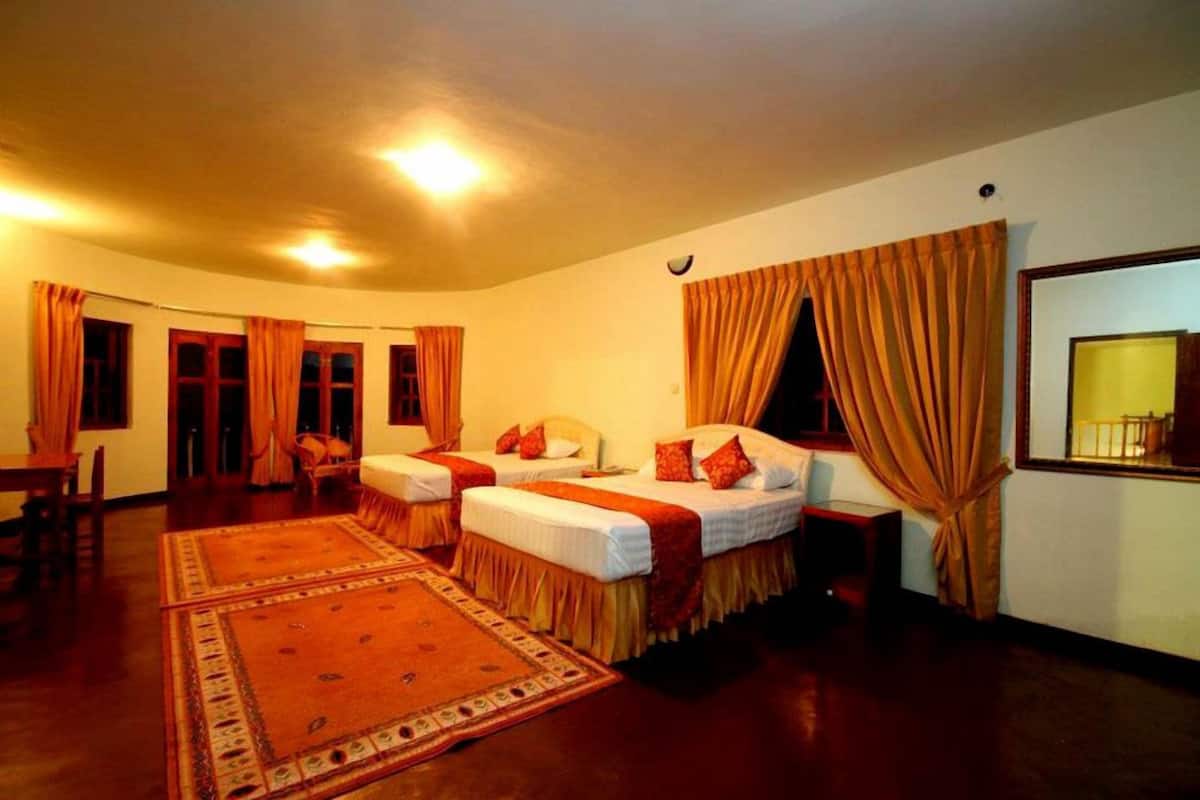 Habitación de hotel con dos camas individuales, un espejo grande y un comedor con mesa y sillas.