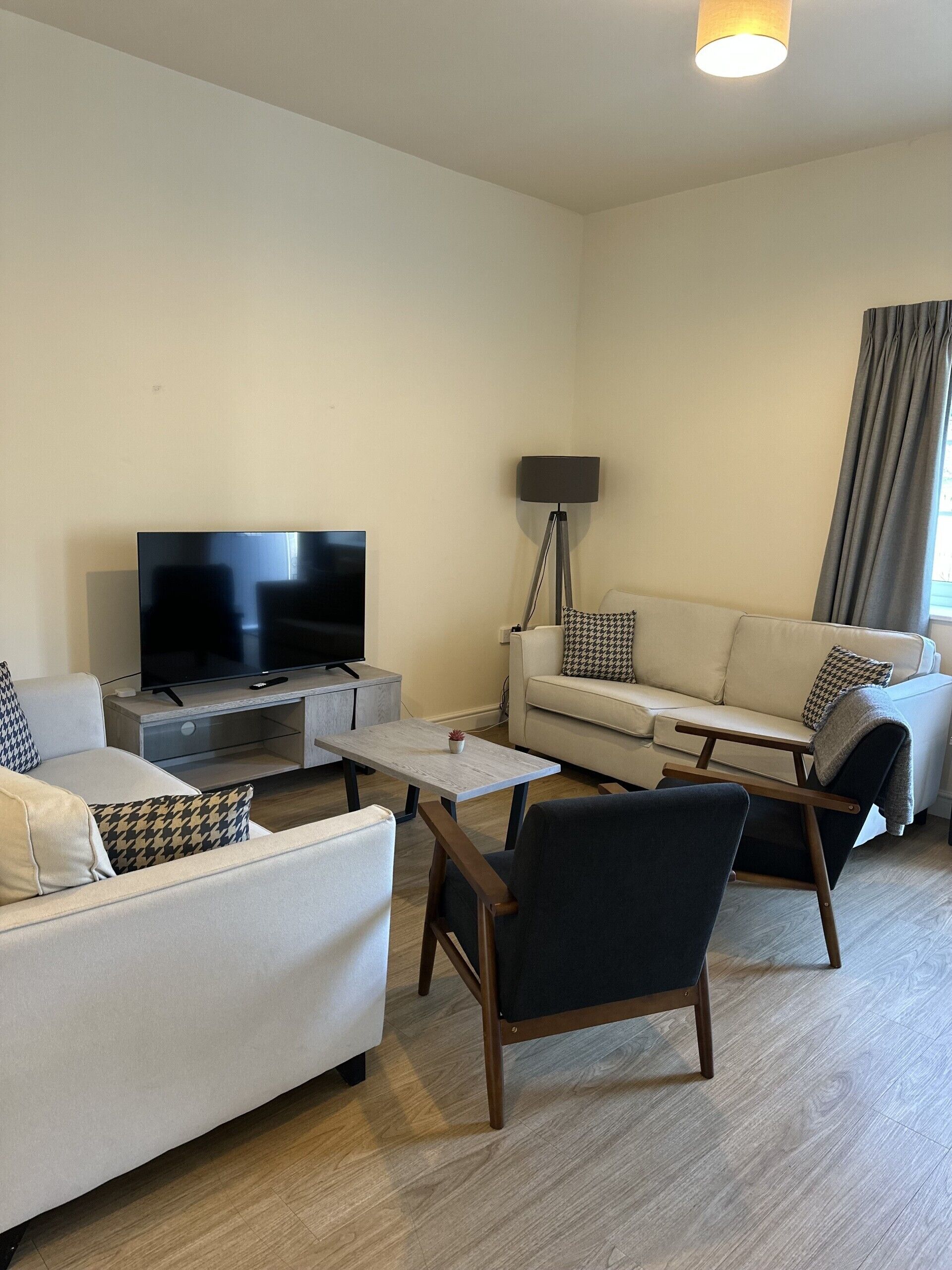 A modern living room with a flat-screen TV, a sofa, a coffee table, and a floor lamp.