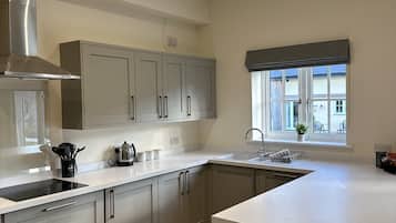 Una cocina moderna con gabinetes grises, una campana de acero inoxidable, un horno empotrado y una ventana con vistas al exterior.