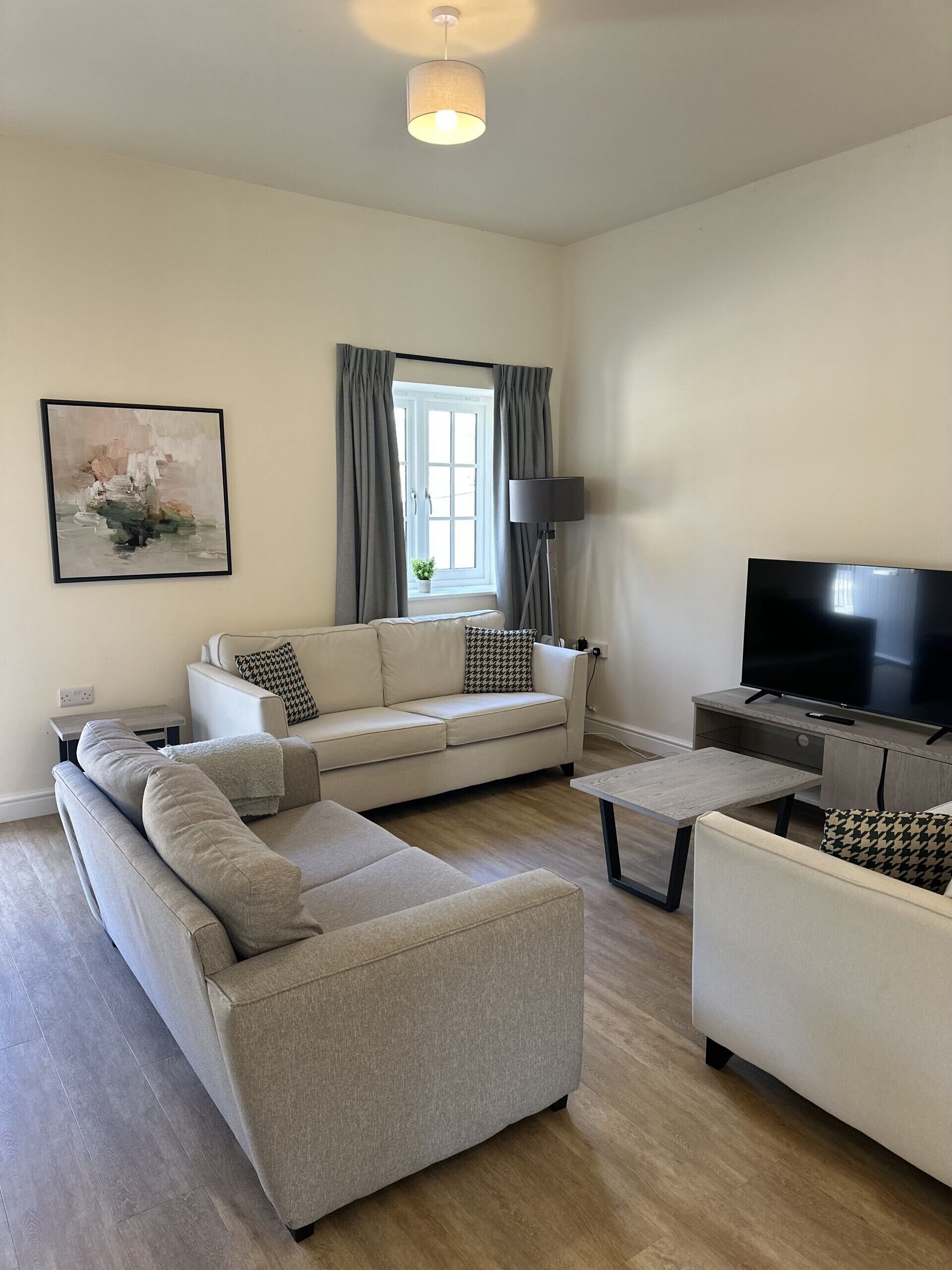 Un salon moderne avec un canapé d’angle, une table basse, un téléviseur et un lampadaire.