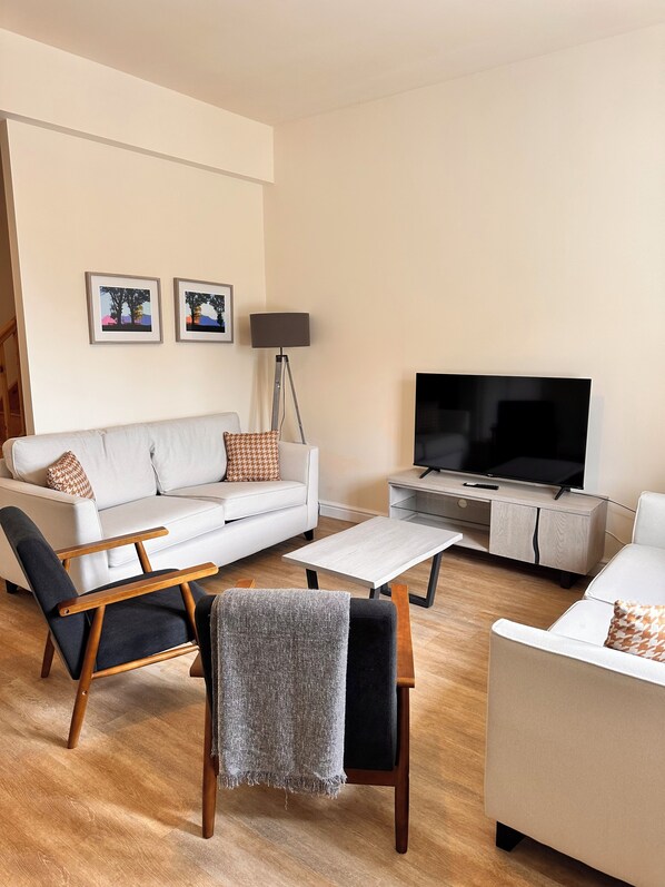 Ein modernes Wohnzimmer mit einem weißen Sofa, einem Couchtisch, einem Fernseher und einer Stehlampe.
