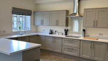 A modern kitchen with grey cabinets, a central island, and a stainless steel range hood.