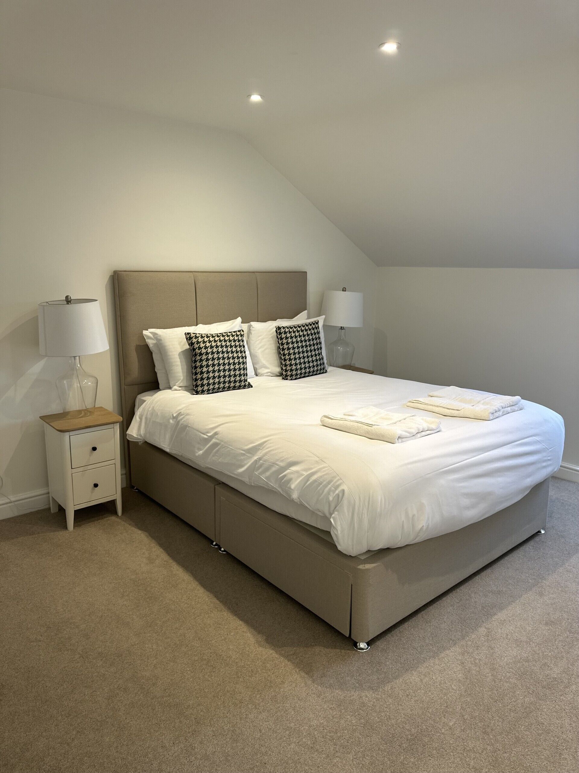 Una camera da letto con un letto grande, due comodini con lampade e un soffitto a falde.