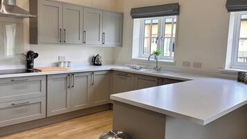 Une cuisine moderne avec des meubles gris, une hotte en acier inoxydable, un grand îlot central et une fenêtre offrant une belle vue.