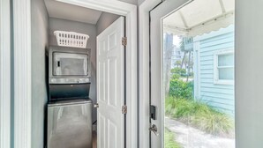 A compact laundry room with a washer, dryer, and a white laundry basket on the wall. - Adorable Upstairs 2 BR Nantucket 6AB (Destin)