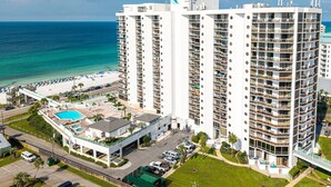 A high-rise hotel with multiple balconies, a swimming pool, and a beach view. - Gorgeous Surfside 708B (Miramar Beach)