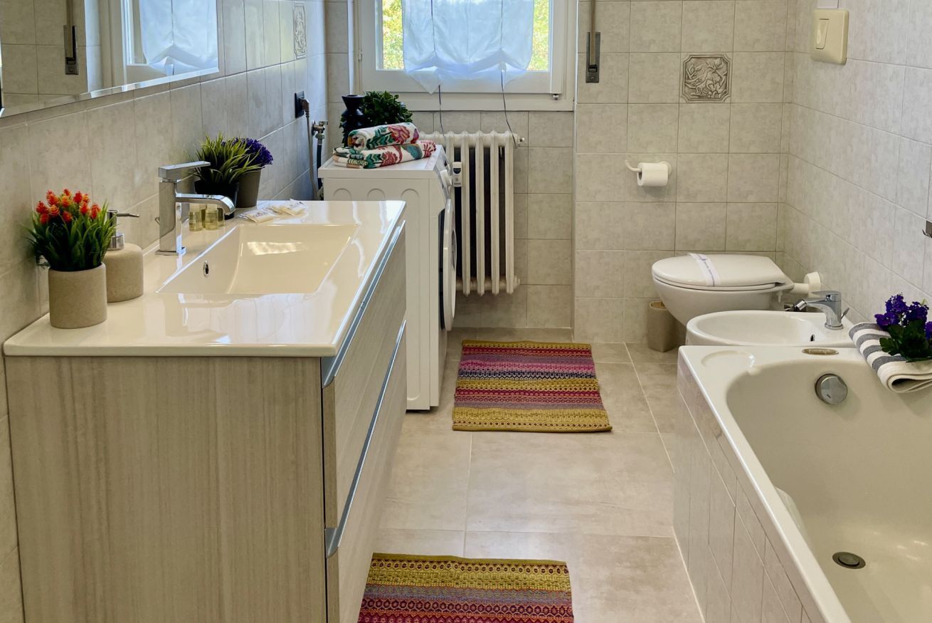 A modern bathroom with a sink, toilet, bathtub, and a radiator.