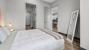 A bedroom with a bed, a bedside lamp, and a door leading to a bathroom.