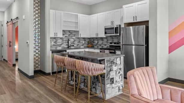 A modern kitchen with white cabinets, stainless steel appliances, and a central island with bar stools.