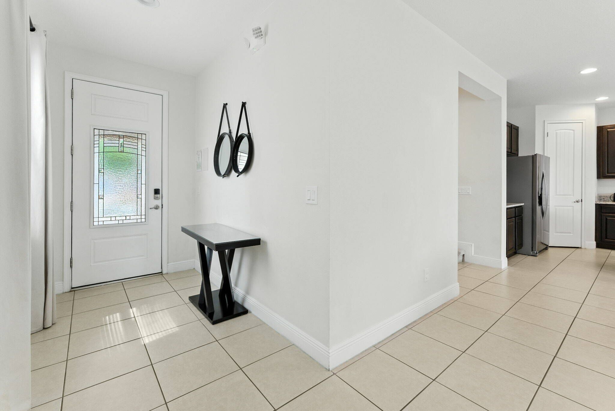 A modern kitchen with white walls, a tiled floor, and a black table.