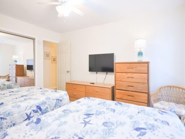 Une chambre d’hôtel avec deux lits, une télévision, une commode en bois et une chaise.