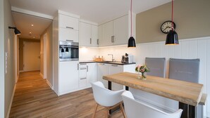 Eine moderne Küche mit weißen Schränken, einer Holz Arbeitsplatte und zwei Pendelleuchten.