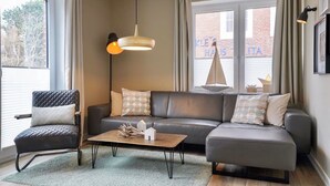 Ein modernes Wohnzimmer mit einem Ledersofa, einem Holztisch und einem schwarzen Sessel.