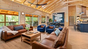 A spacious wooden interior with a dining area, kitchen, and seating arrangements. - New 4-King Cabin w/ Cave View, Hot Tub, Fire Pit (Frenchburg)