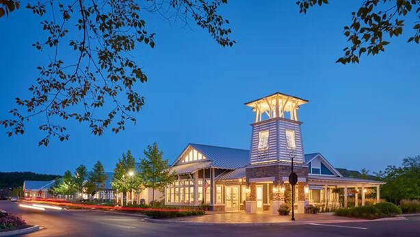 A hotel with a prominent tower, a covered patio, and a well-lit entrance. - Dog‑Friendly (Only 1) Bayside Condo w/ Pool & Gym (Selbyville)