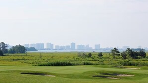 A golf course with bunkers and a city skyline in the background. - Dog‑Friendly (Only 1) Bayside Condo w/ Pool & Gym (Selbyville)