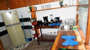 A compact kitchen with a refrigerator, stove, sink, and various kitchen appliances. - Paradiselodge - Romantic Hideaway, next to Nauyaca (Platanillo de Baru)