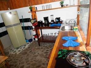 A compact kitchen with a refrigerator, stove, sink, and various kitchen appliances.