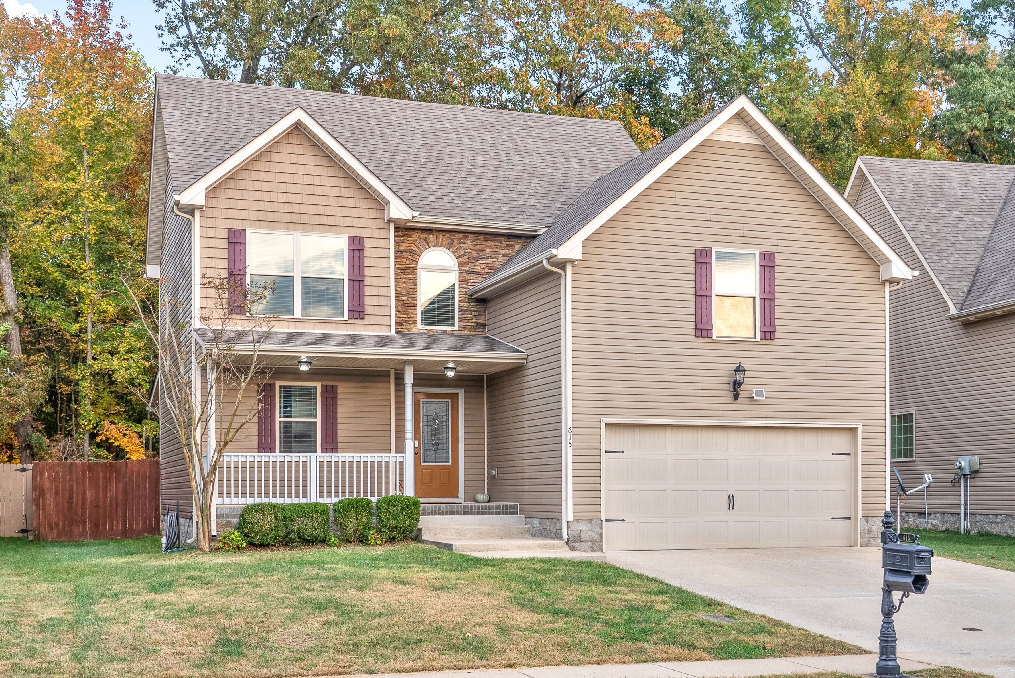 A two-story house with a front porch, a garage, and a well-maintained lawn.