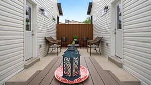 A patio with a wooden bench, two wicker chairs, a table, and a decorative lantern.