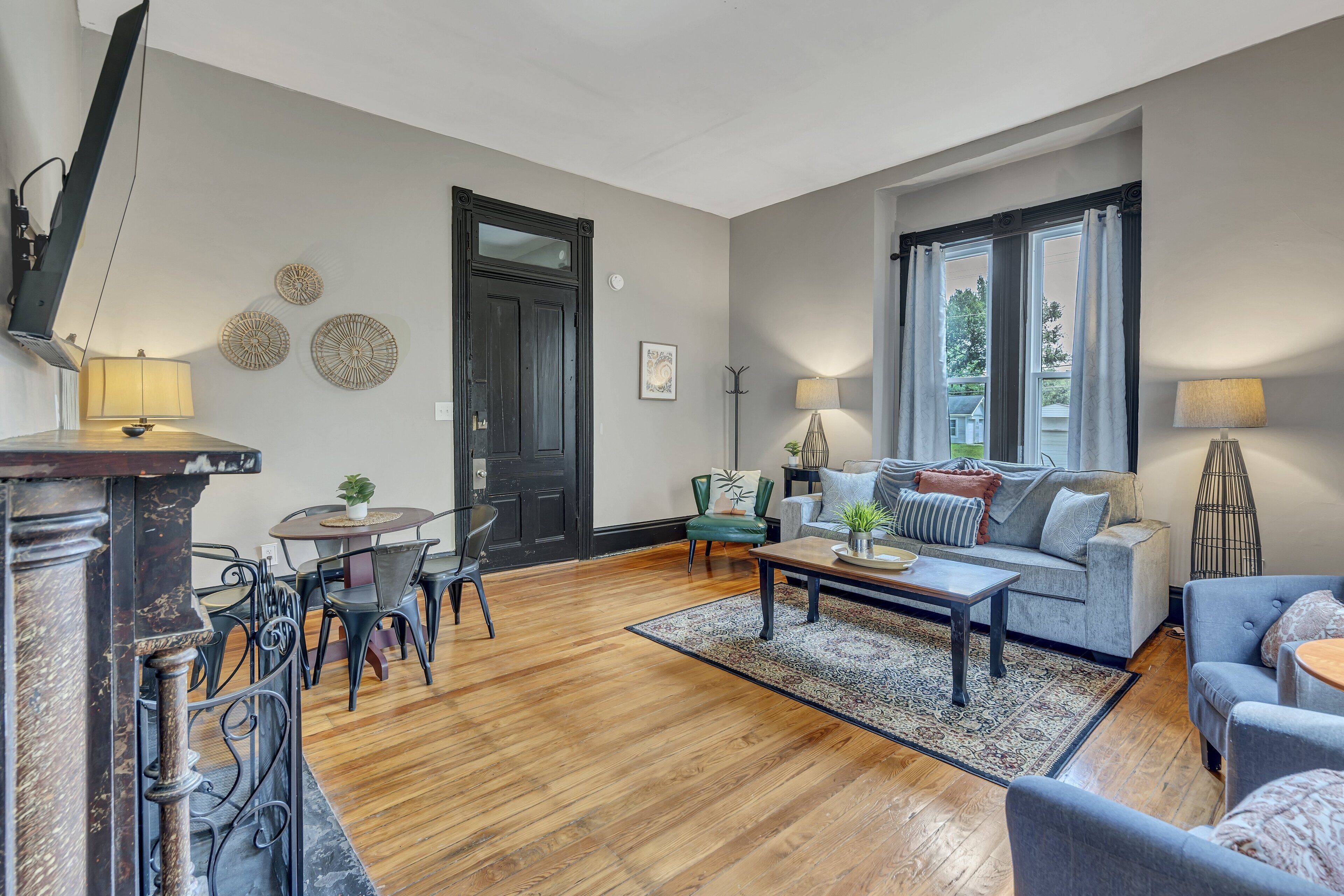 Un salon avec un plancher en bois, un canapé gris, une table basse et un téléviseur fixé au mur.