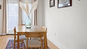 A dining area with a wooden table, chairs, a vase with pampas grass, and a patterned rug. - Loft #210 (540 N 2nd St) (Fredericton)